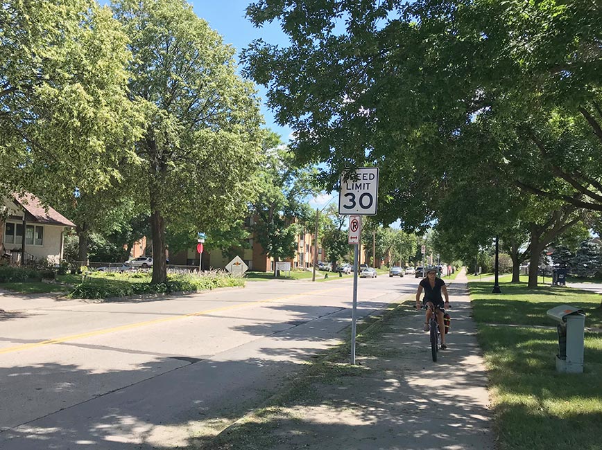 Biker on a paved bike path alongside a street