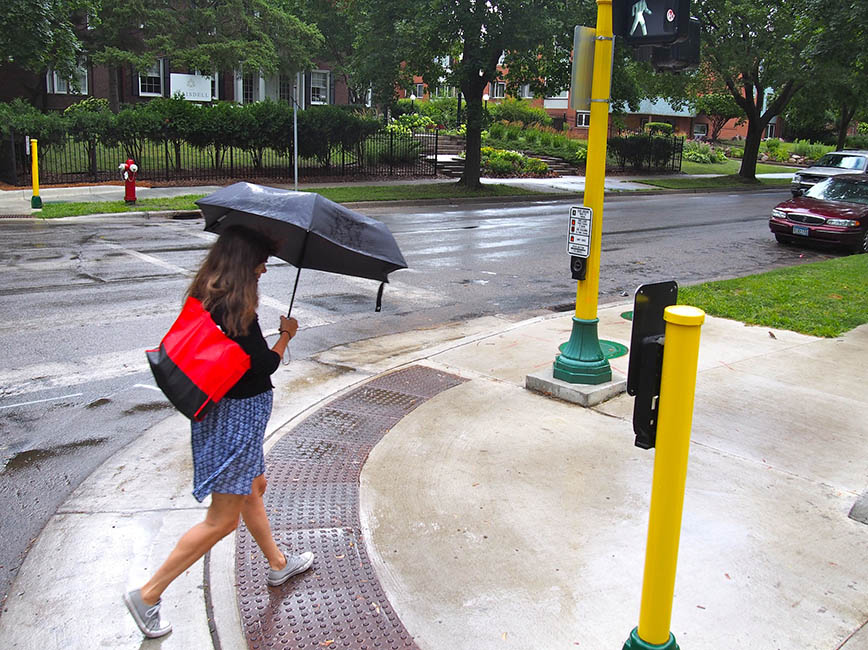 A person at a signalized intersection with Accessible Pedestrian Signals and Pushbutton
