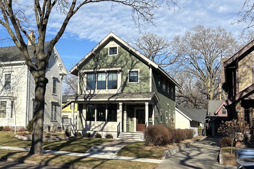 Outside of a green house with trees and other houses surrounding