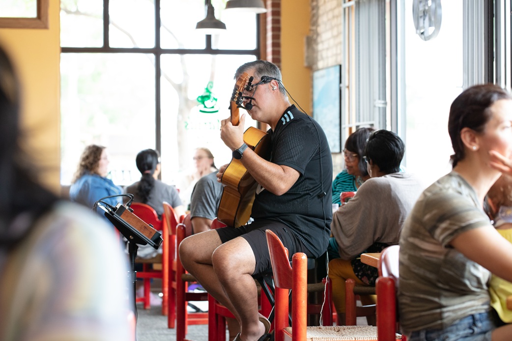 Person playing guitar on a stool