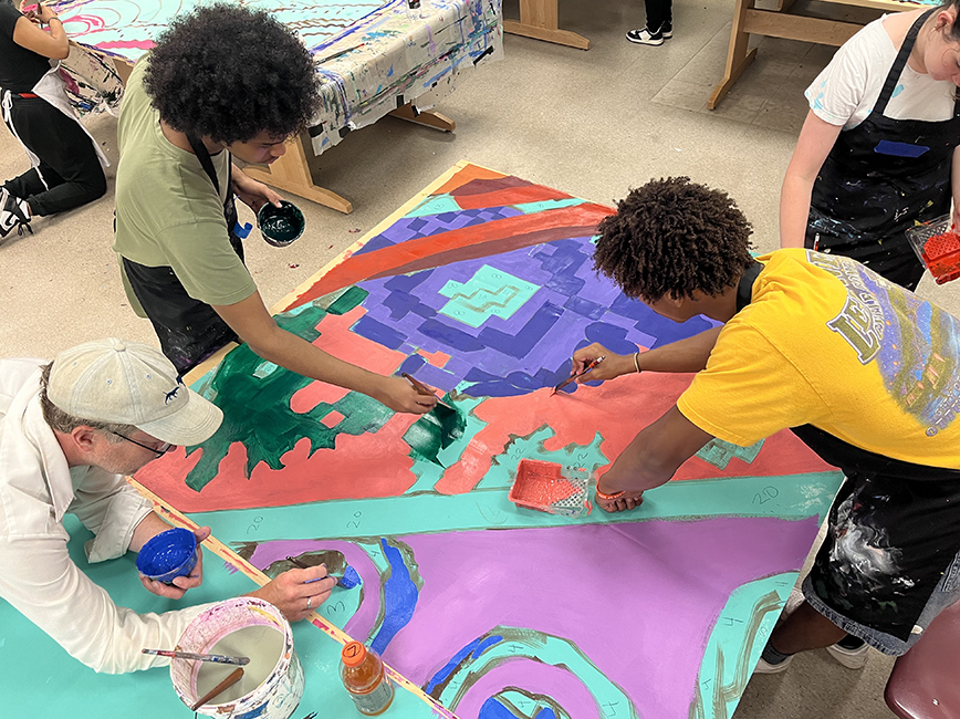 Student engaged in working on a large painting.