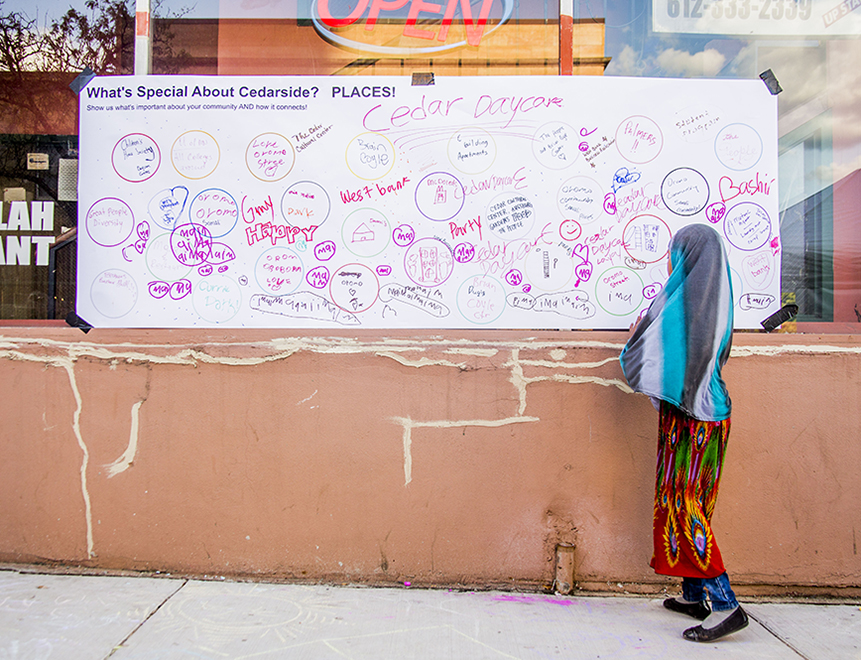 Young girl drawing on whiteboard posted on a building. Art by Justin Sengly.