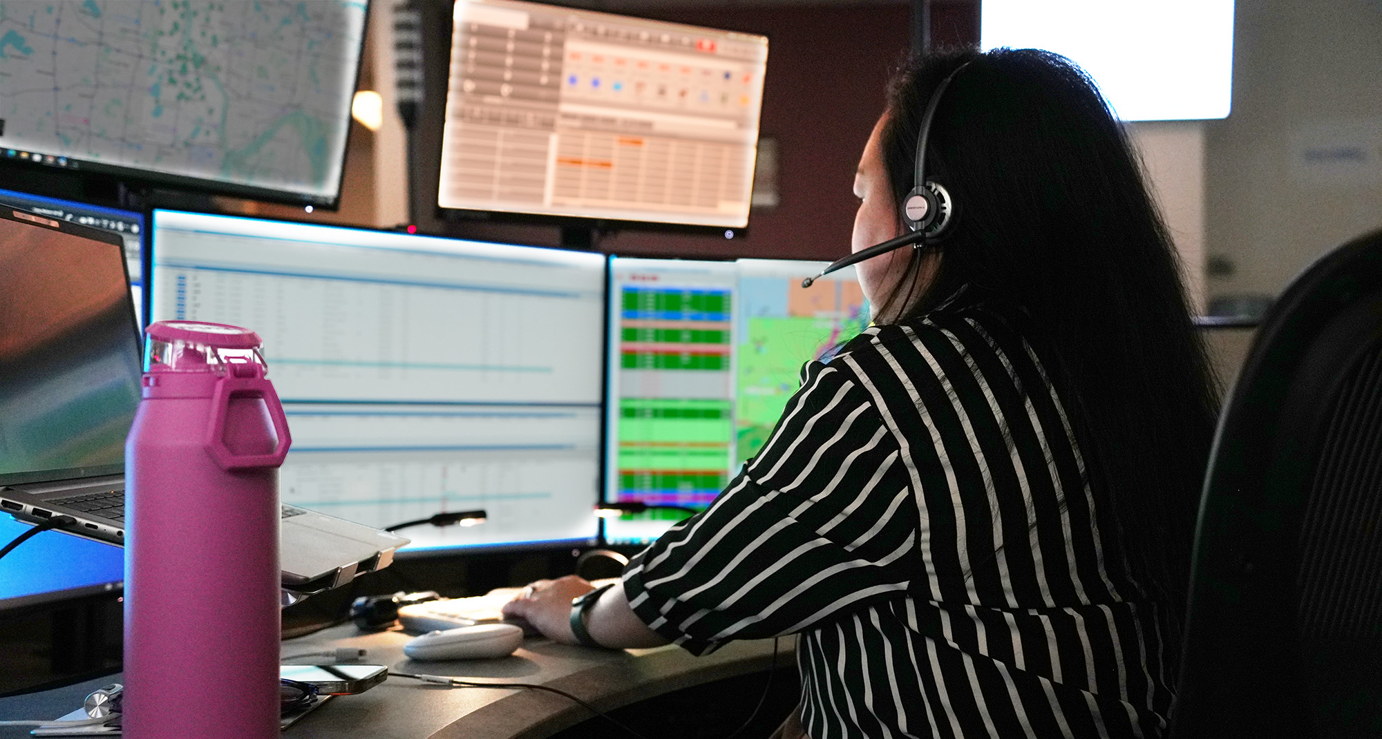 A telecommunicator wearing a headset and working on computer