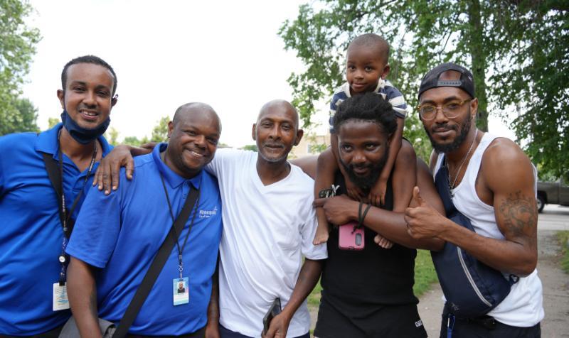 Two Community Safety Ambassadors posing with community members in the E. Franklin Ave. area.
