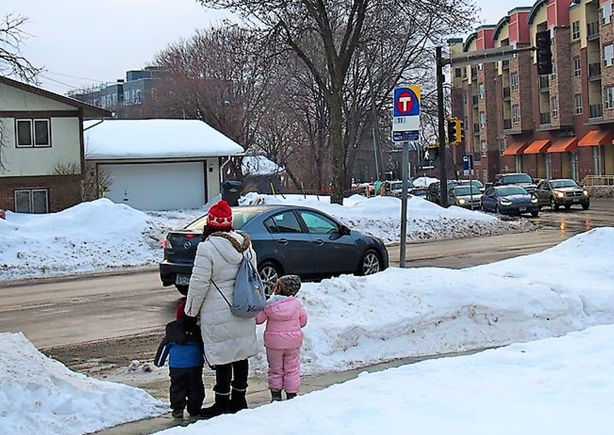 Parent and children near bus stop waiting to board or cross