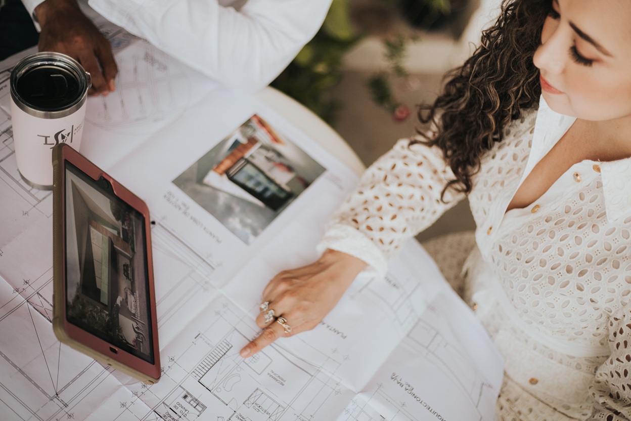 Person reviews architectural floor plans on a table with a tablet