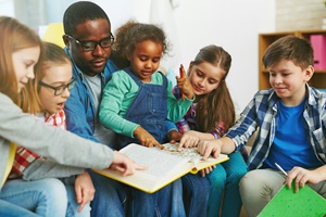 Group of children reading a book with teacher
