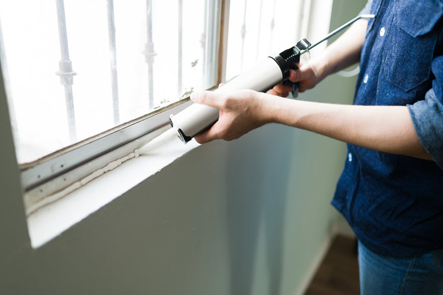Person putting caulk on window