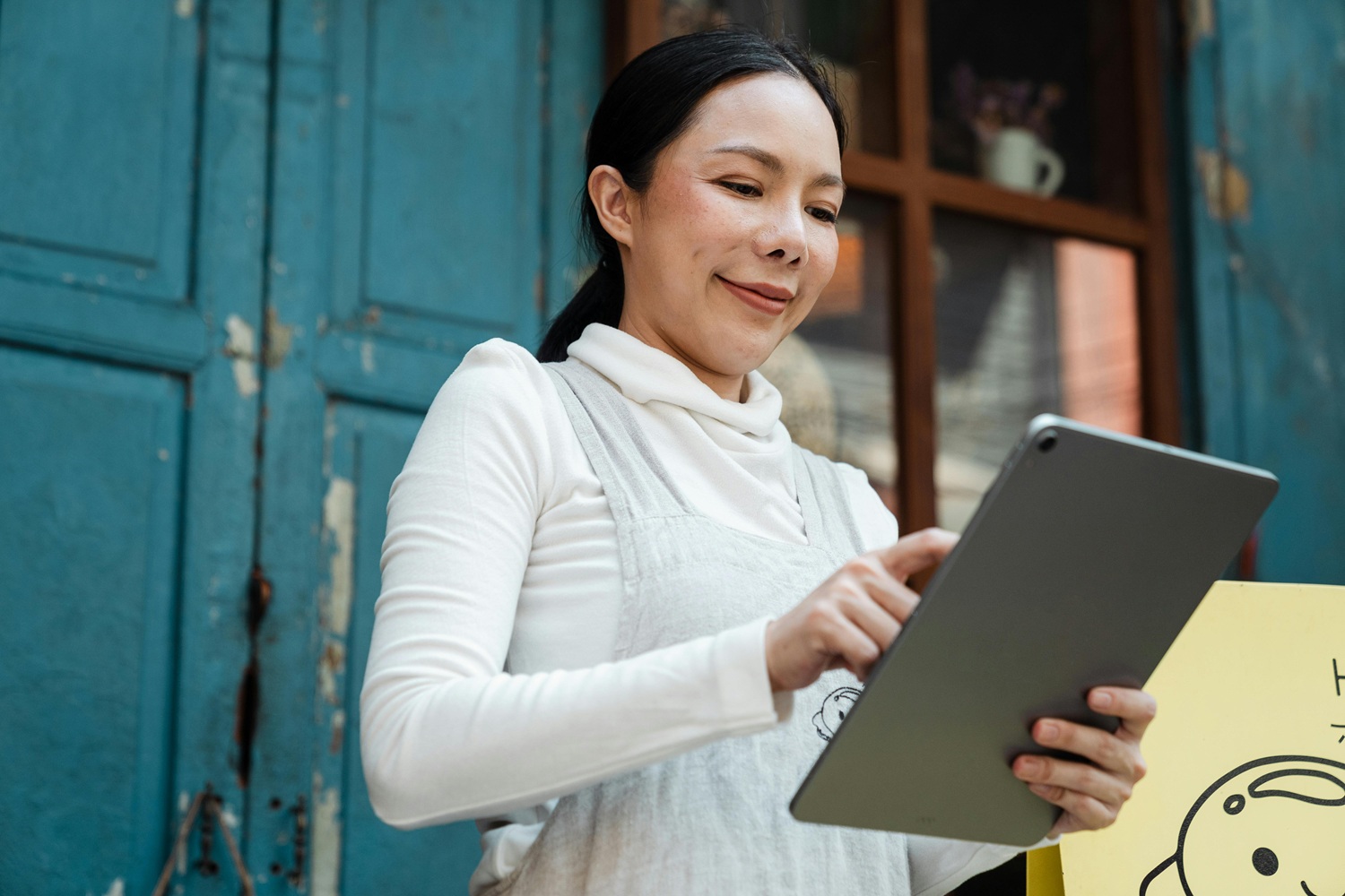 Person in white long sleeve shirt holding silver tablet computer