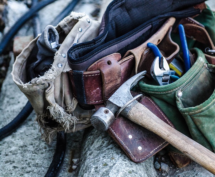 tool belt laying on the ground with a hammer